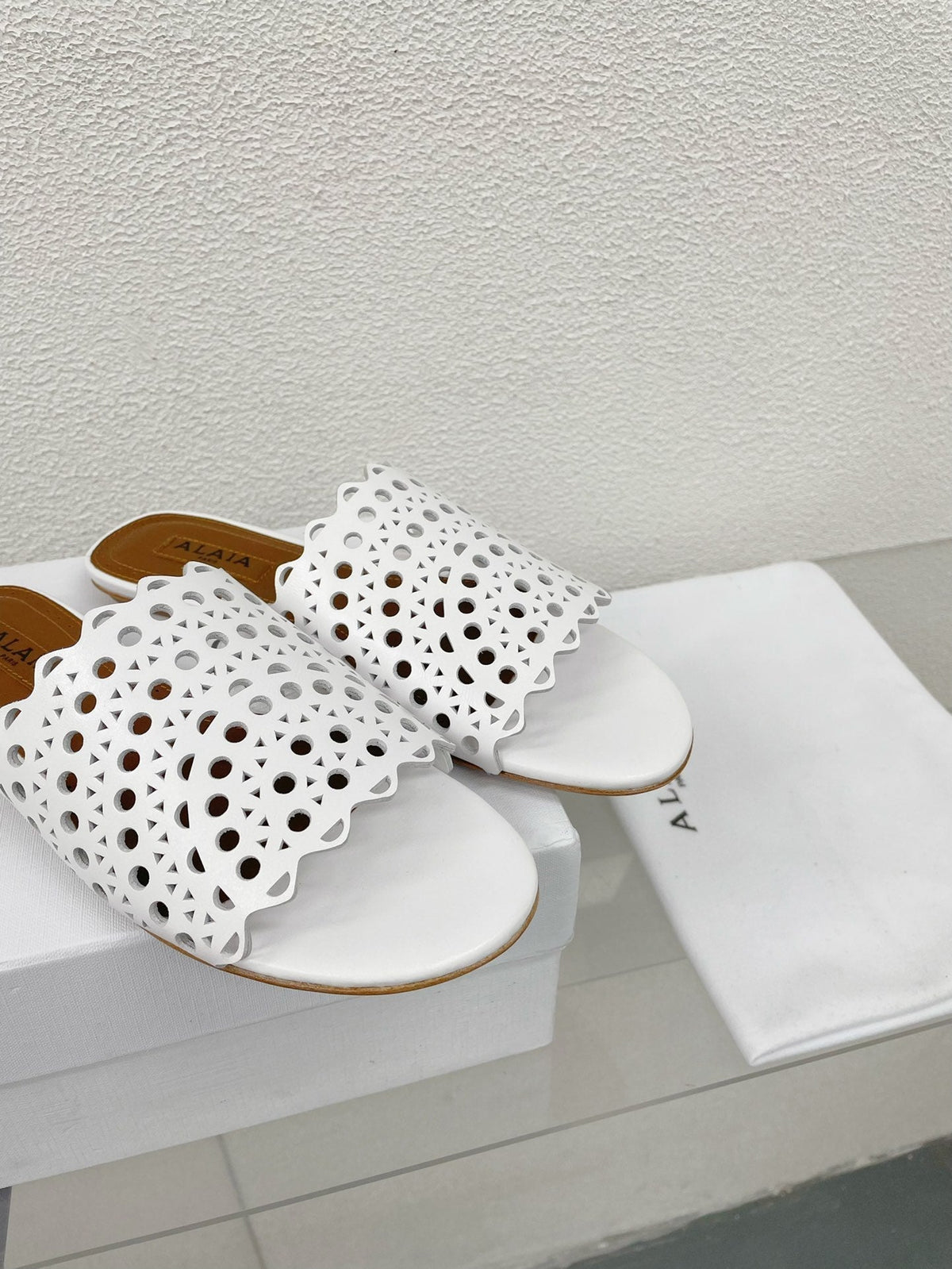 ALAIA VIENNE FLAT MULES IN WHITE LAMBSKIN